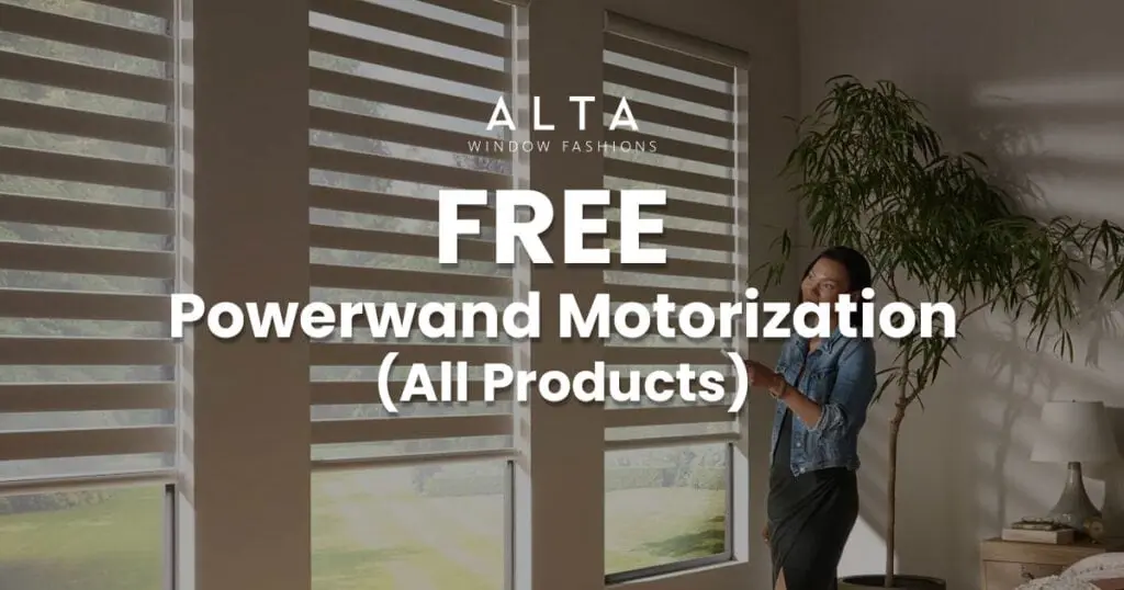 Woman standing near large window with blinds, promoting free Powerwind motorization for all products by ALTA Window Fashions.