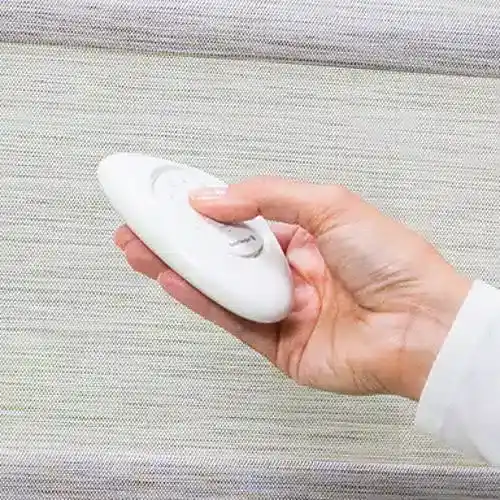 Soft white remote control for window blinds or drapes, showcasing ease of operating window treatments with Blinds West products.