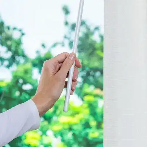 Rod and pulley system for blinds operation with lush green background, showcasing professional window treatment solutions.