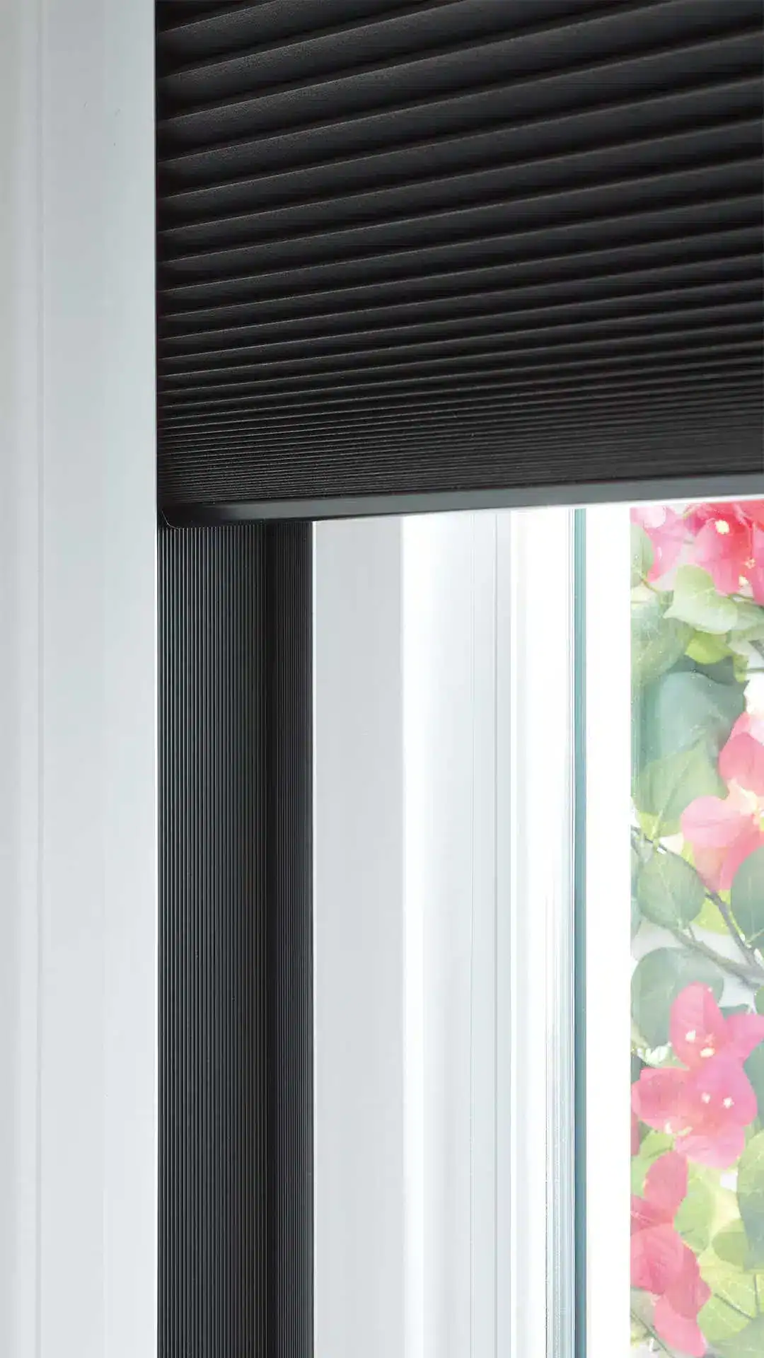 Black horizontal window blinds with a sleek, modern design and textured finish, installed in a bright room with floral accents, perfect for enhancing home decor and controlling natural light.