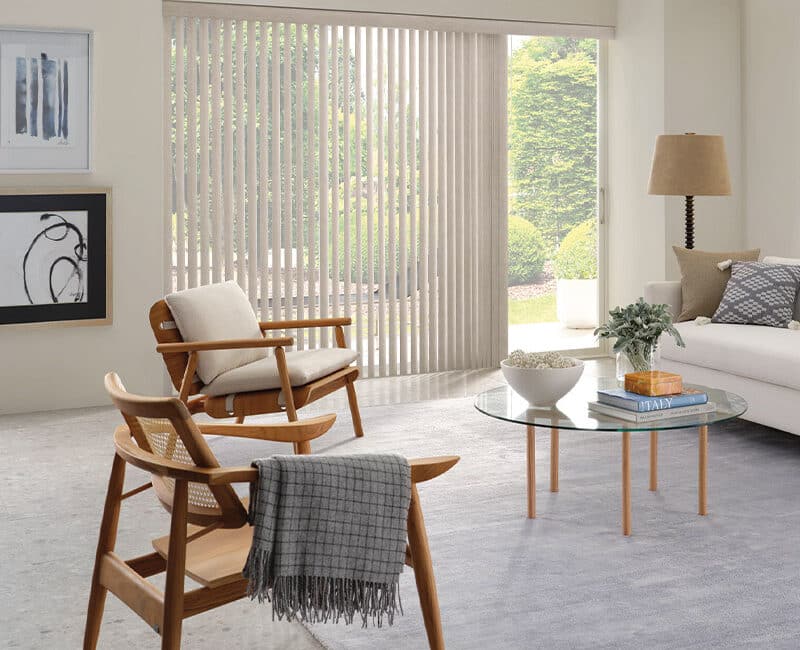 Luxurious living room with custom vertical blinds, modern furniture, and natural light, showcasing premium window treatments by Blinds West.