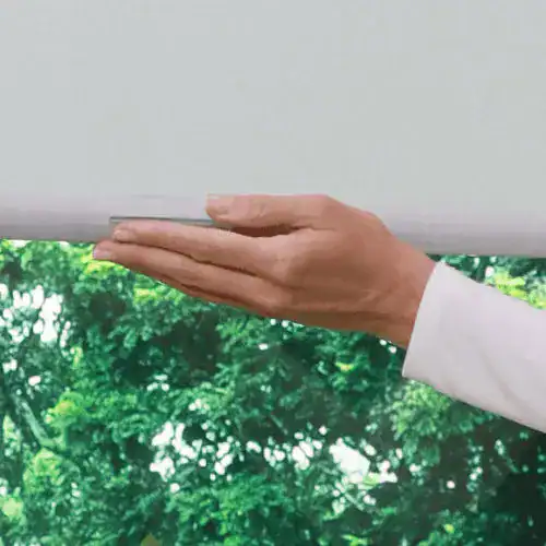 White window blind being adjusted by a person with a white sleeve, showcasing professional window treatment services.