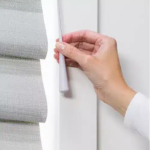 Rolled gray window blinds with white wall, offering light control and privacy, suitable for home or office window treatment solutions.