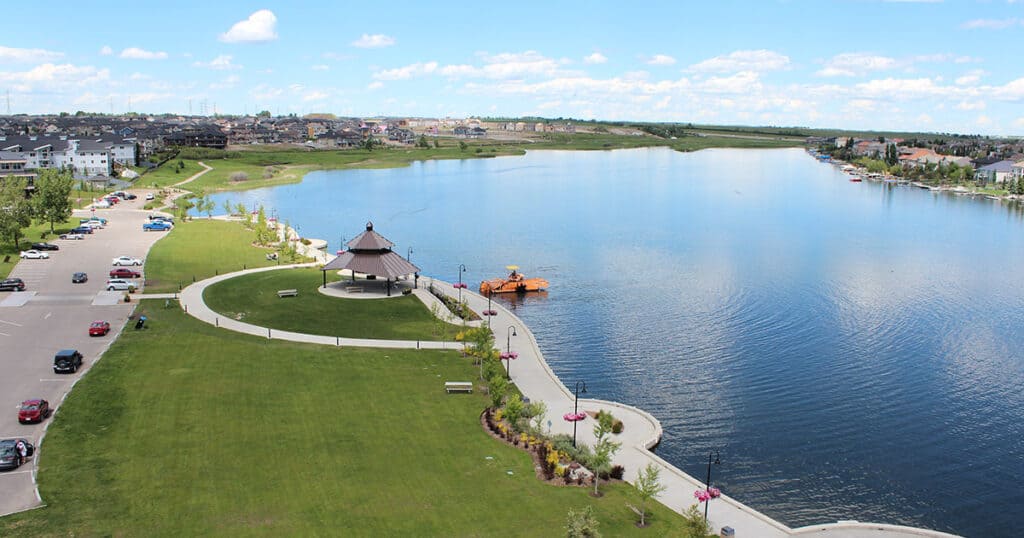 A scenic lakeside park featuring a walking path, boat dock, picnic areas, and lush green spaces, ideal for outdoor activities and relaxation near residential neighborhoods.